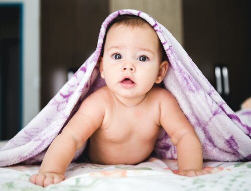 Cute baby crawling with blanket on head